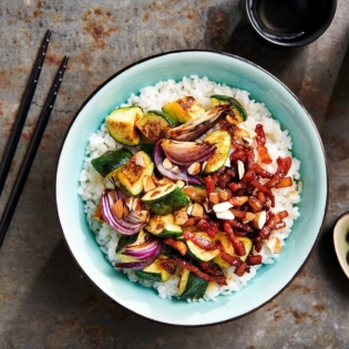 Poké bowl met honing-sojaspekjes, geroosterde courgette en amandel